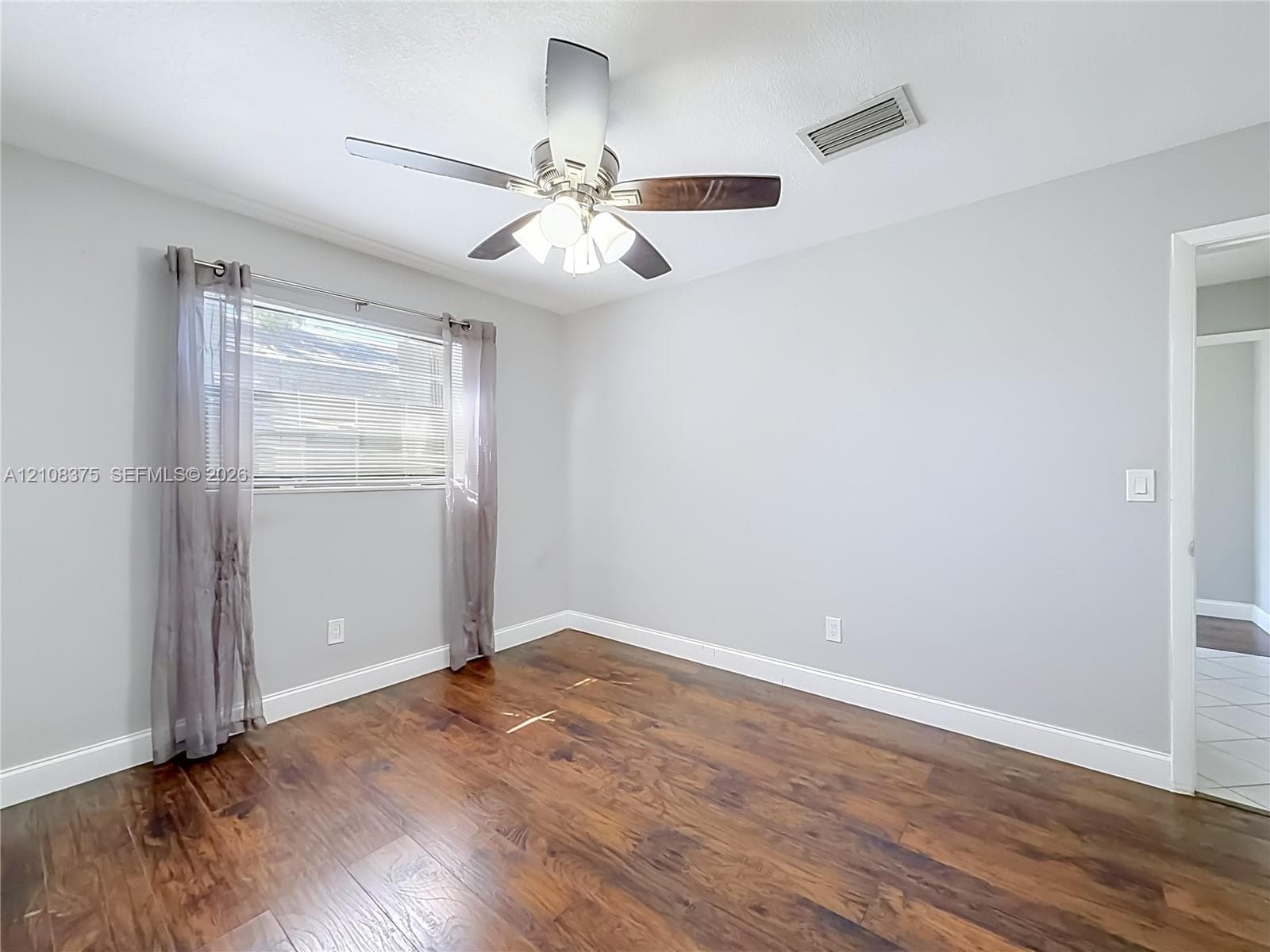 Wood-finish flooring, neutral wall tones, and a ceiling fan with integrated lighting
