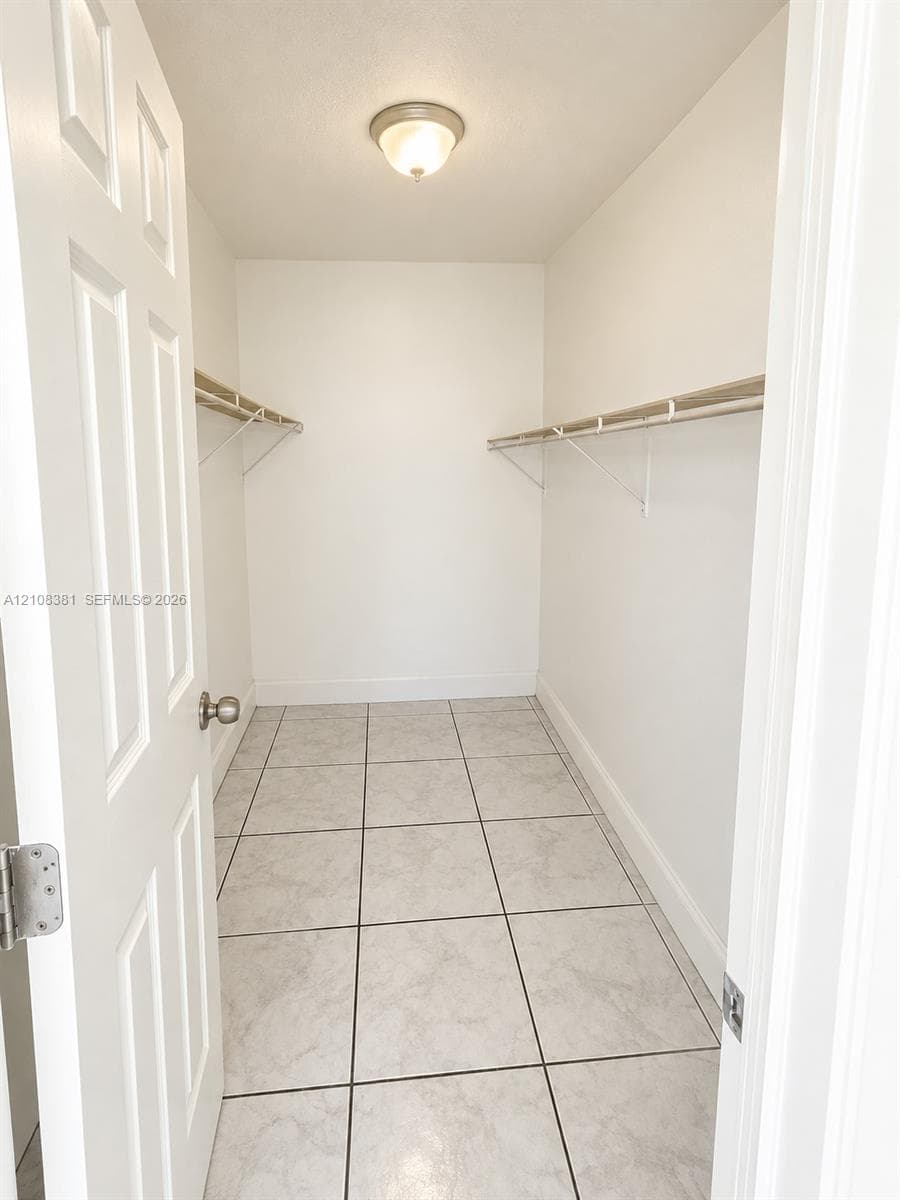 Walk-in closet featuring ceramic tile flooring, dual-level wire shelving, and a flush-mount ceiling light fixture