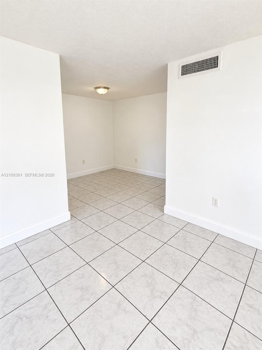 Interior space featuring neutral white walls and square stone-finish tile flooring