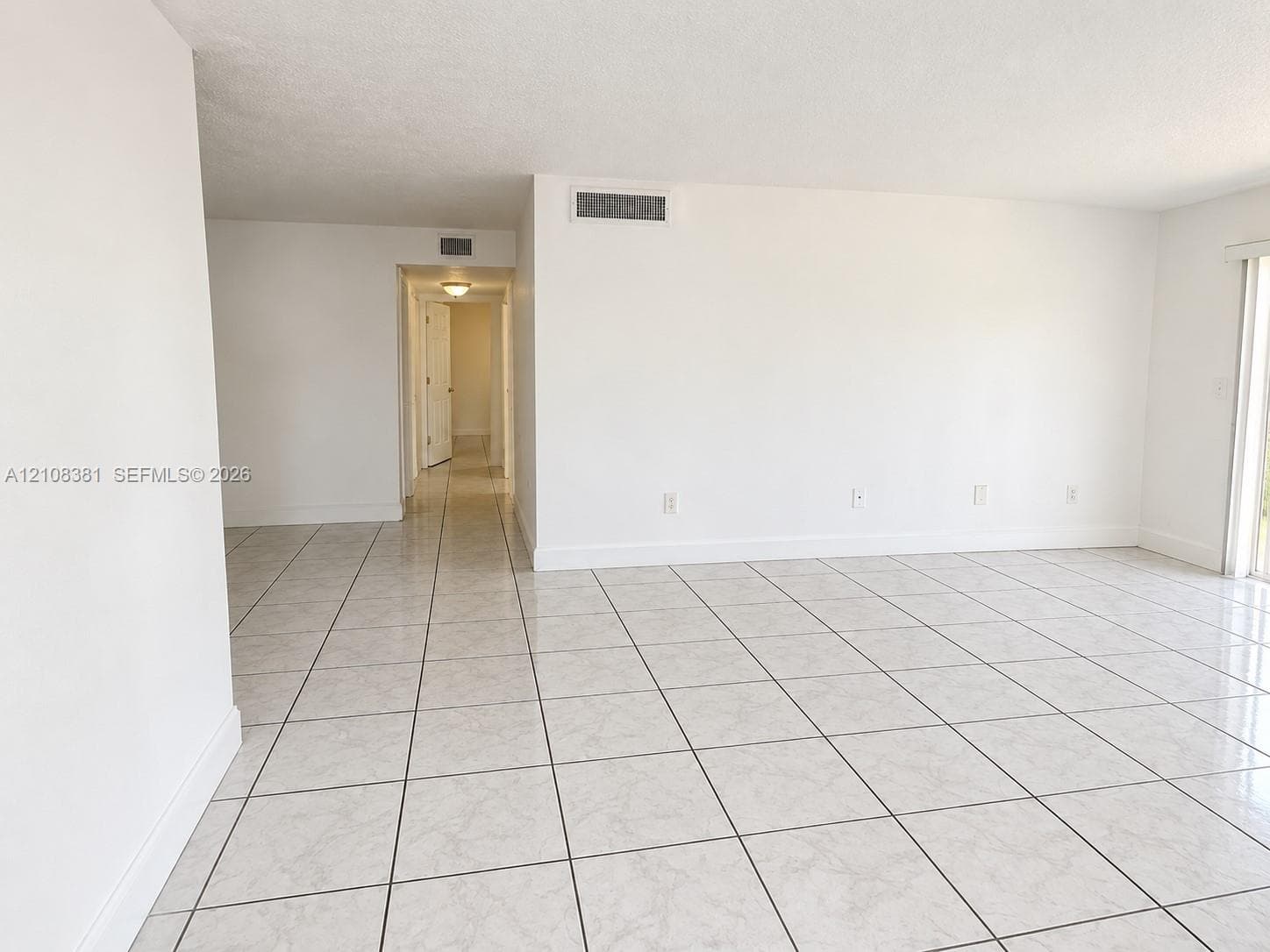 Neutral-toned ceramic tile flooring, smooth white wall finishes, and glass sliding door access to exterior space