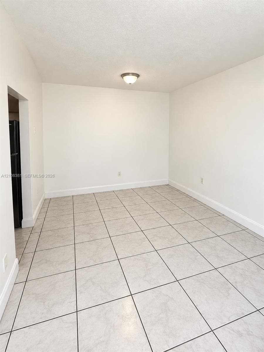 Neutral-toned ceramic tile flooring, crisp white walls, and a center-mounted flush mount light fixture