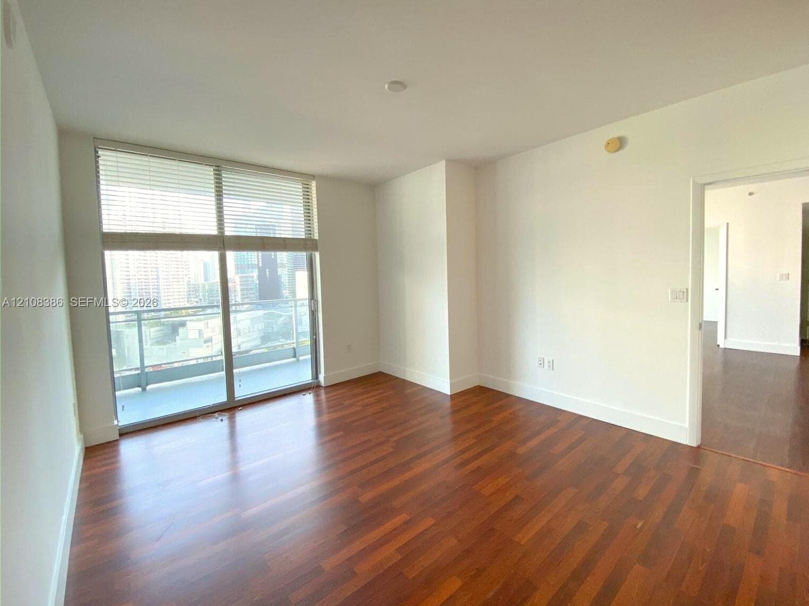 Living space featuring wood-finish flooring, floor-to-ceiling windows, and a glass-paneled balcony