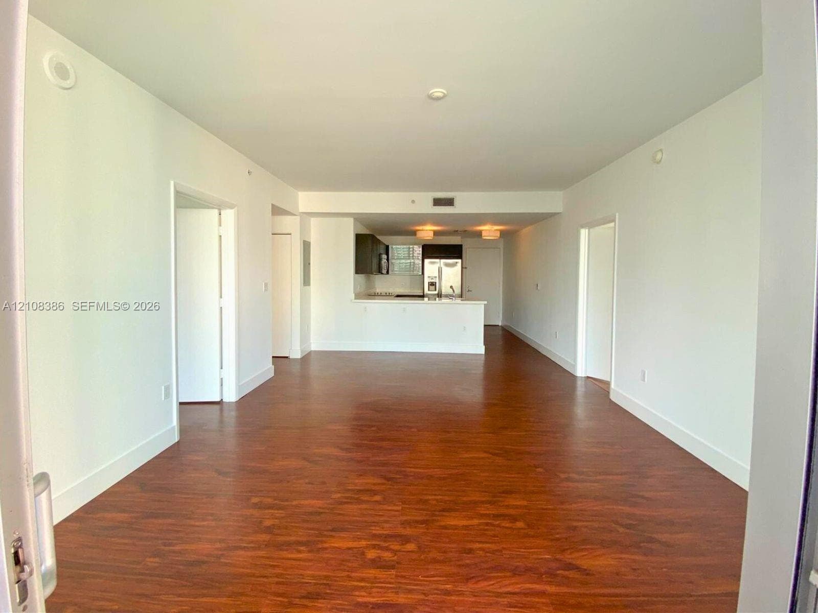 Open-concept interior featuring wood-finish flooring, recessed ceiling lighting, and a kitchen peninsula with a white countertop