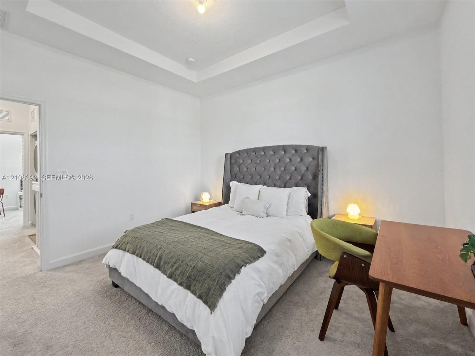 Room featuring a tray ceiling and neutral-toned wall-to-wall carpeting