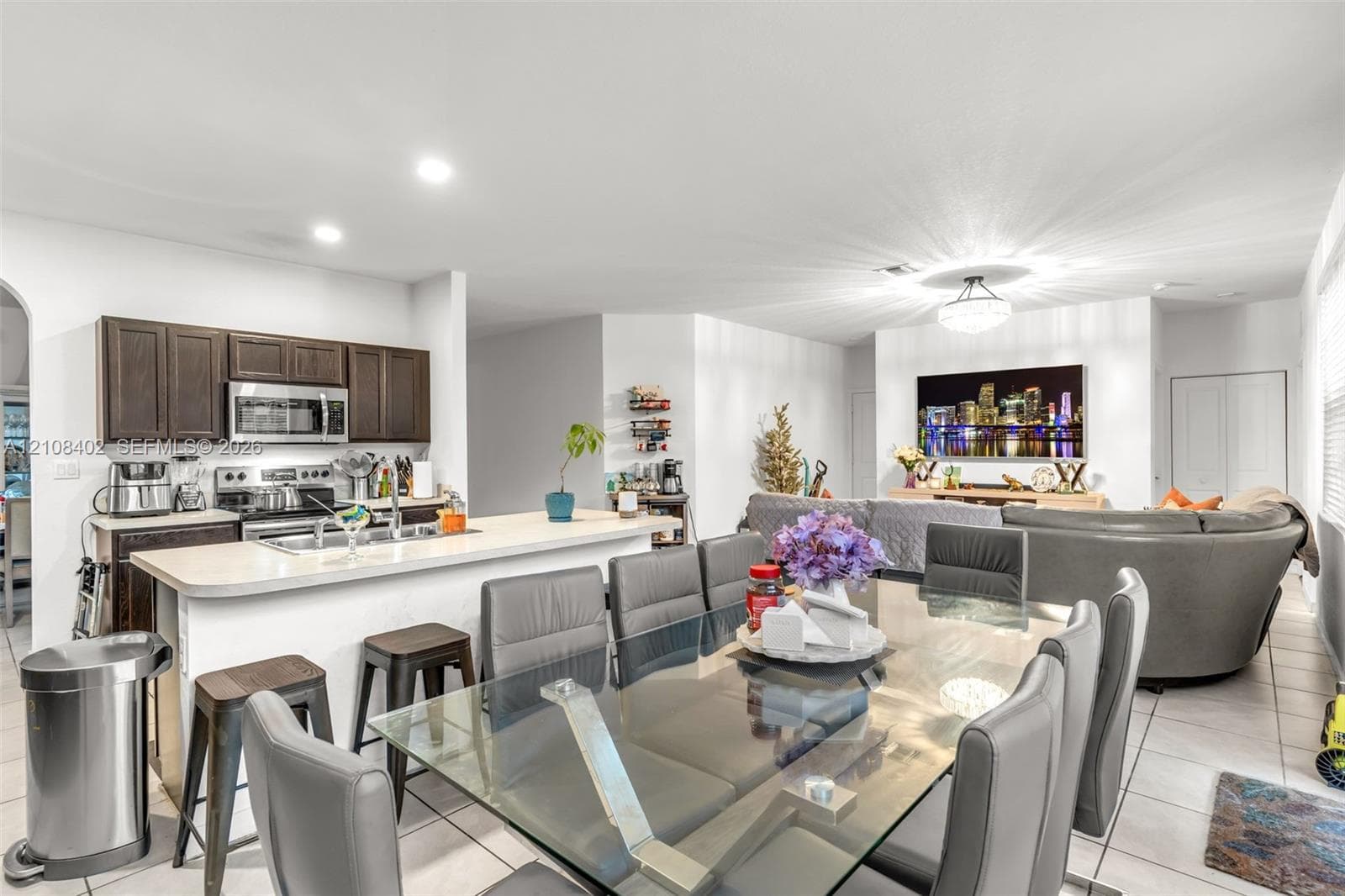 Kitchen featuring dark wood cabinetry, an integrated breakfast bar, and stainless-steel appliances, complemented by tile flooring and recessed lighting