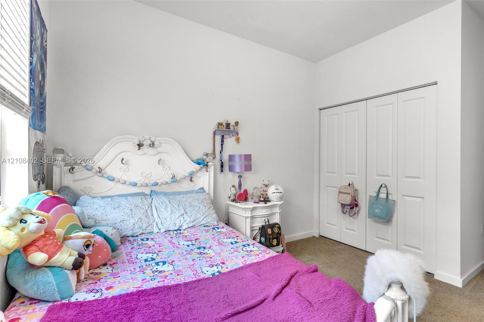 Room featuring neutral-toned carpeting, high ceilings, and a double-door closet