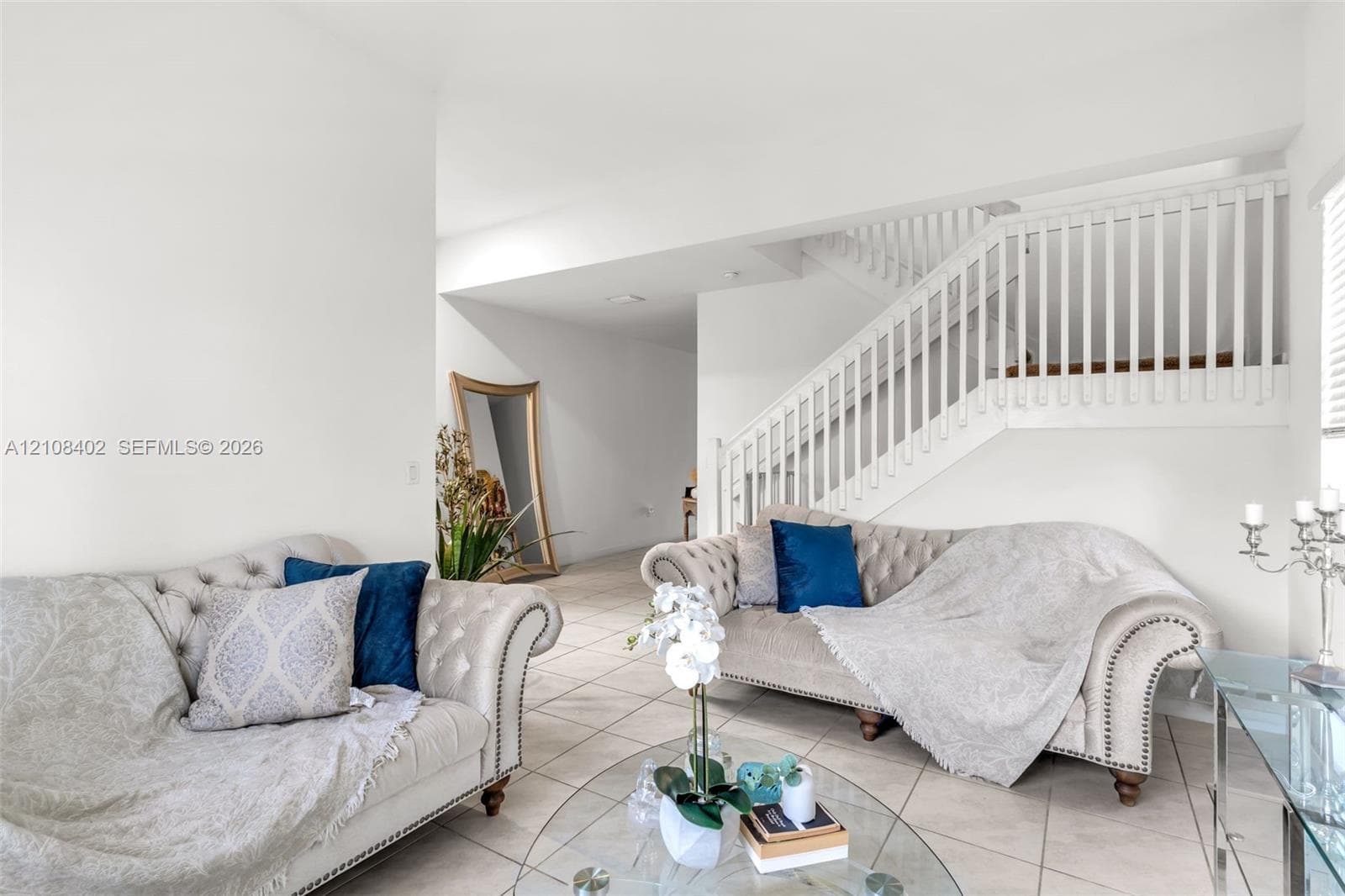 Open-concept interior featuring large-format ceramic tile flooring and a staircase with white vertical balusters