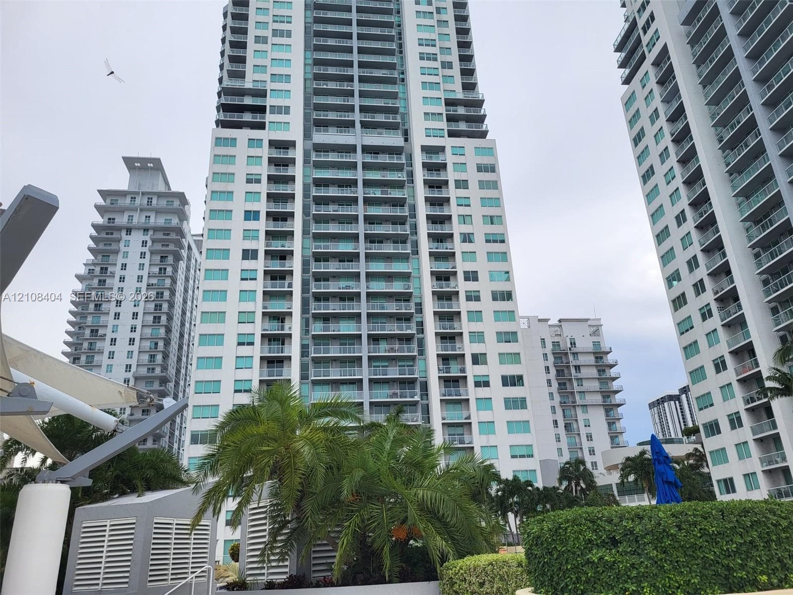 High-rise residential exterior featuring a multi-story glass facade, concrete structural framing, and private balconies with railings