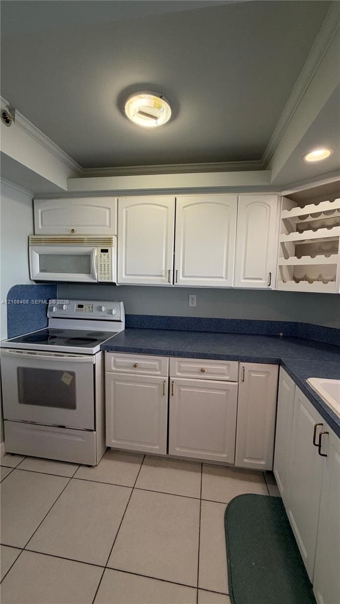 Kitchen featuring white shaker-style cabinetry, a built-in wine rack, solid-surface countertops with an integrated backsplash, and tile flooring
