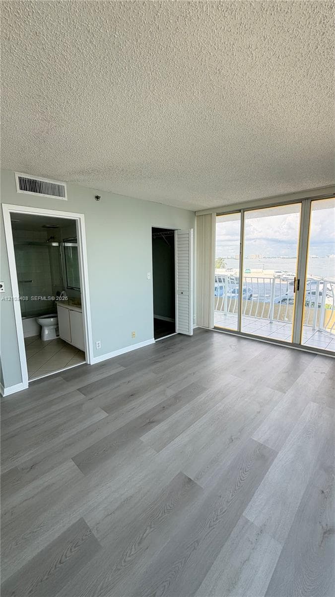Wood-finish flooring, full-height sliding glass doors with balcony access, and dual interior doorways