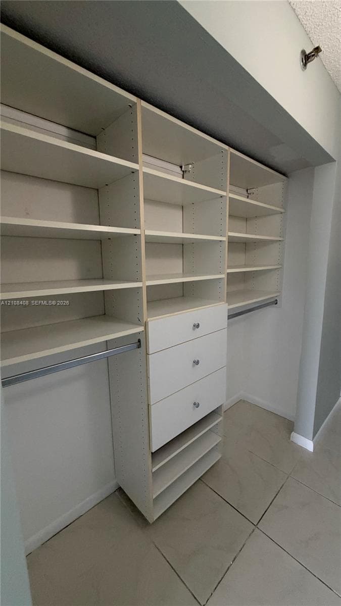 Custom built-in closet organization system featuring adjustable white shelving, integrated drawers with hardware, and metal hanging rods