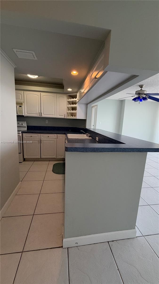 Kitchen featuring white cabinetry, solid-surface countertops, a breakfast bar, built-in wine rack, and tile flooring