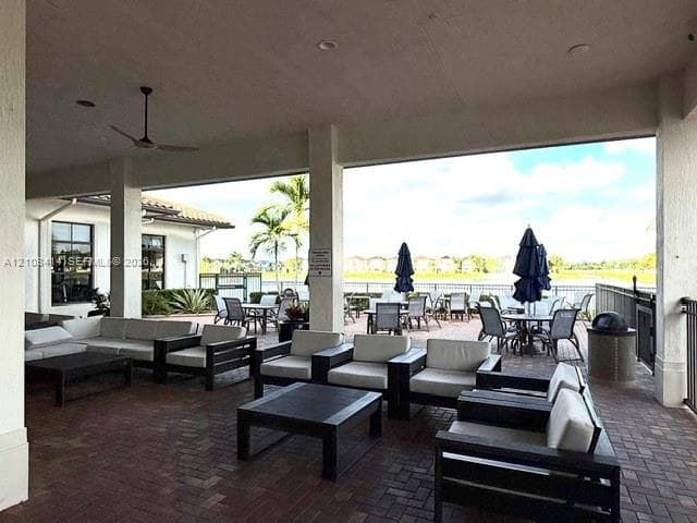 Covered outdoor terrace featuring paver flooring, support columns, recessed lighting, and a ceiling fan