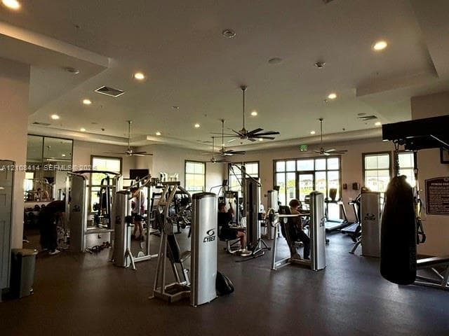 Fitness facility featuring recessed lighting, ceiling fans, multiple large windows, and wall-mounted mirrors