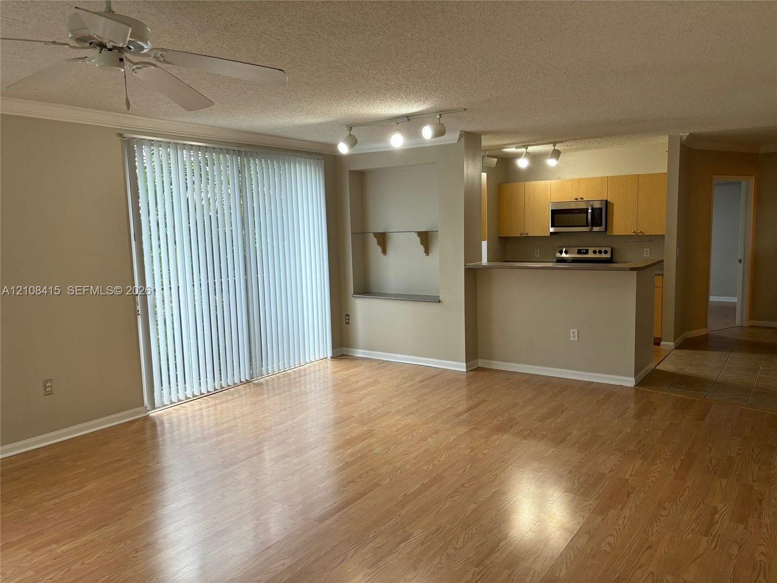 Wood-finish flooring, sliding glass patio door, built-in recessed shelving, breakfast bar, and track lighting