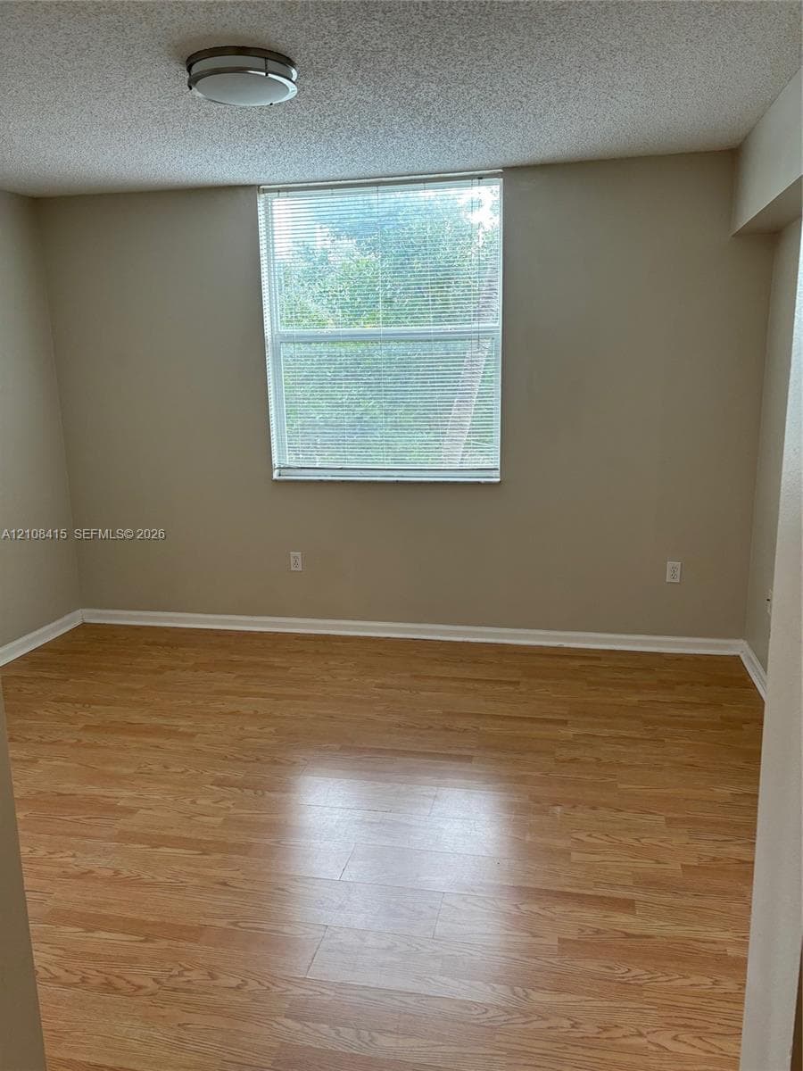 Neutral-toned walls, wood-finish flooring, and a single-pane window with horizontal blinds and integrated flush-mount lighting