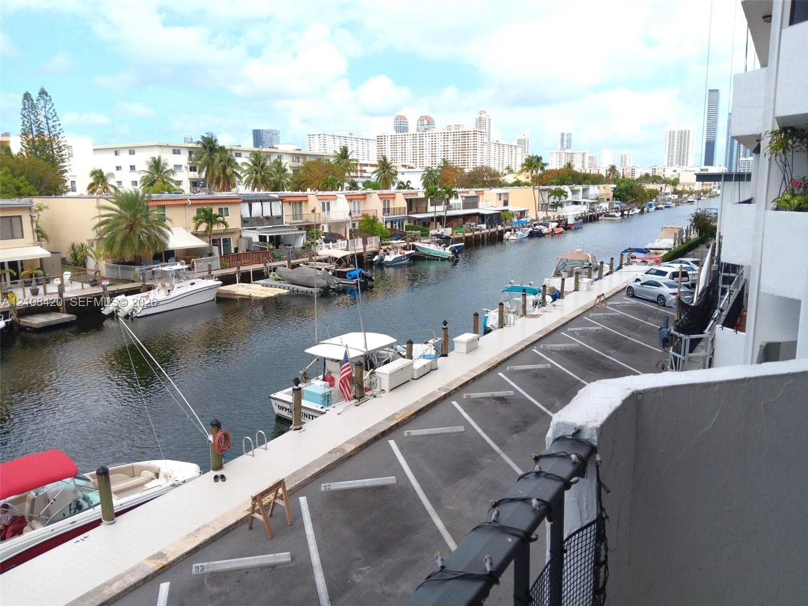 Elevated balcony overlooking a concrete dock featuring assigned parking spaces and direct waterway access