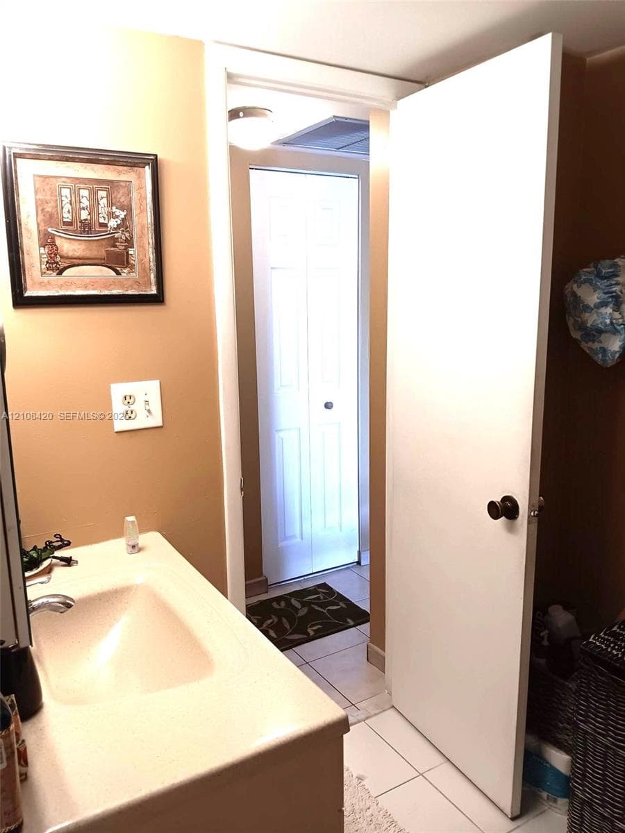 Integrated vanity featuring a solid surface countertop with an oval-inset basin and neutral tile flooring
