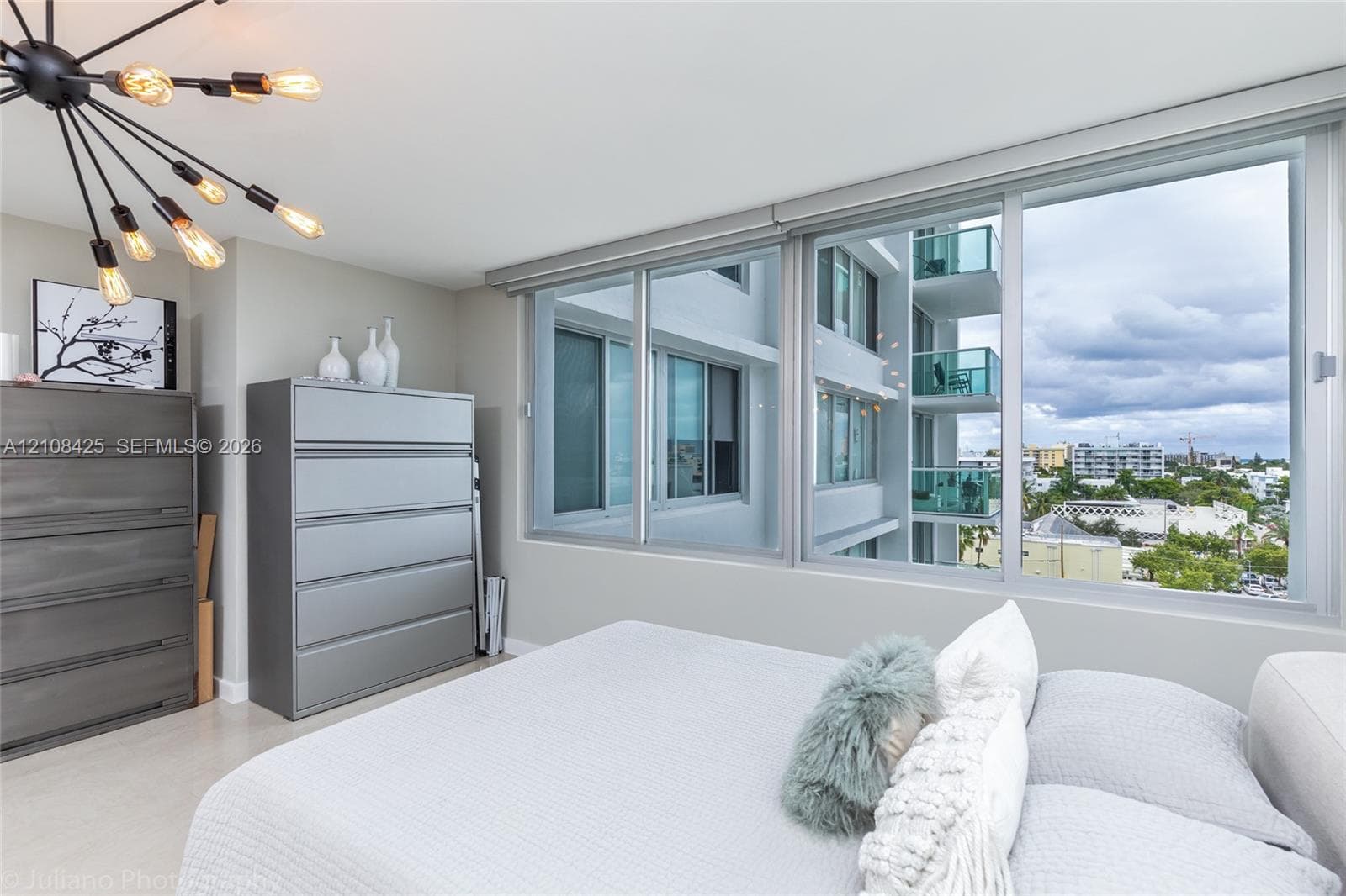 Expansive sliding glass windows, contemporary multi-arm sputnik-style ceiling light fixture, neutral wall color, and smooth-finish flooring