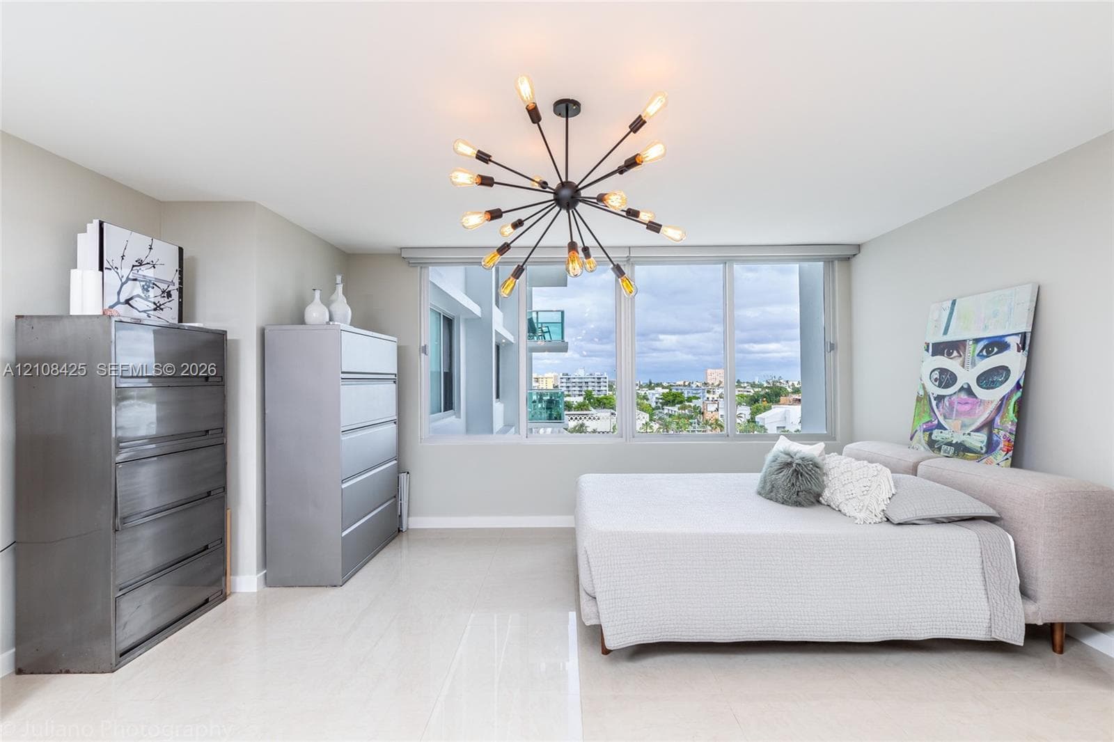 Large-format neutral flooring, expansive floor-to-ceiling windows, and a multi-arm sputnik-style overhead light fixture
