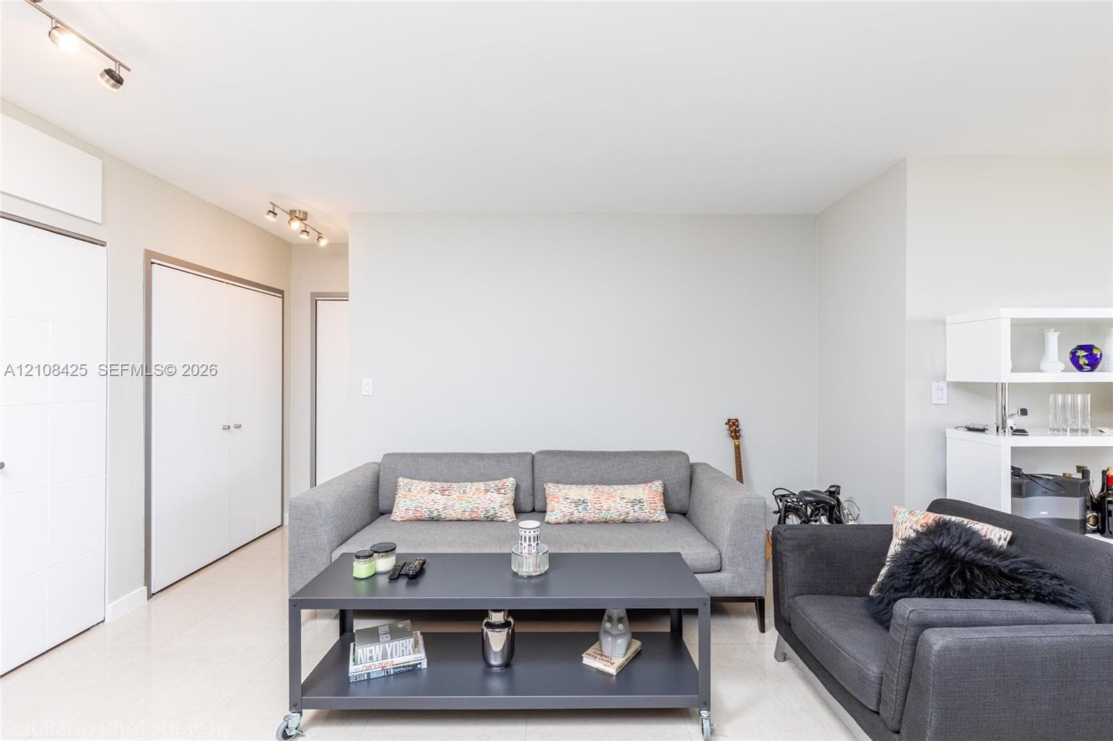 Neutral walls, track lighting, built-in white cabinetry, and smooth flooring