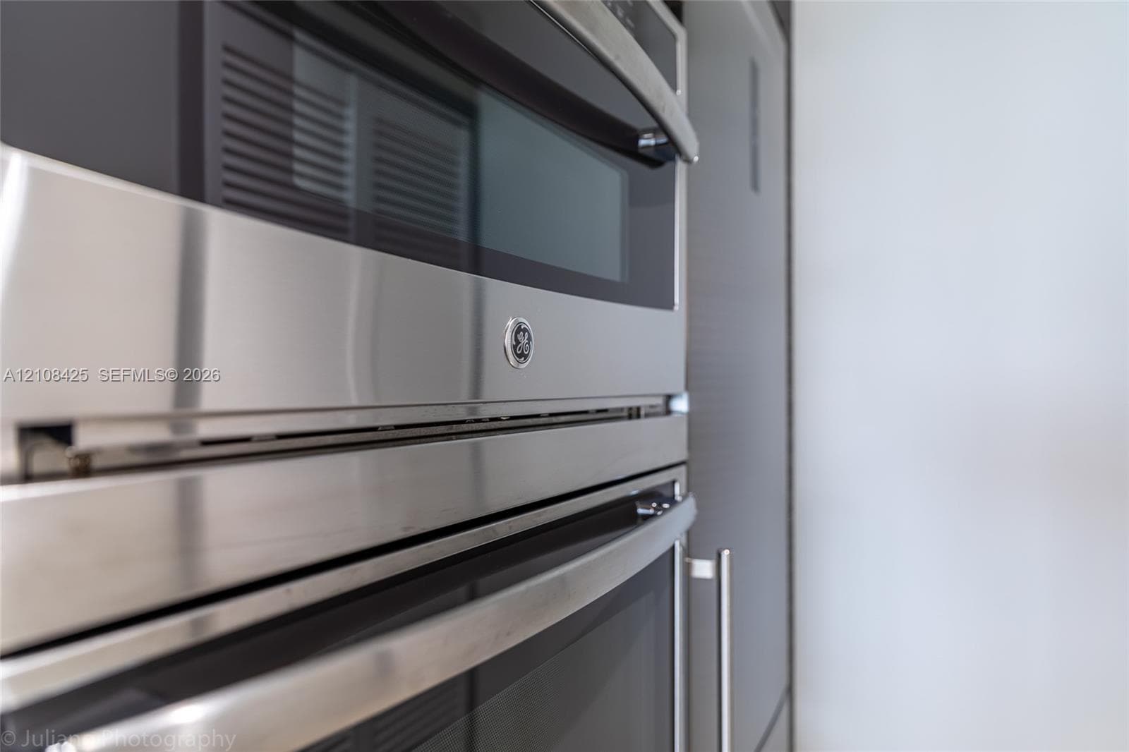 Stainless steel wall-mounted double oven featuring a built-in microwave, integrated touch controls, and sleek handles