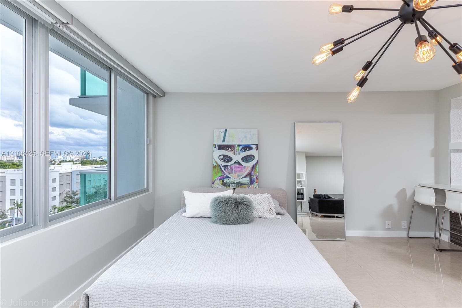 Floor-to-ceiling windows, polished tile flooring, industrial-style multi-arm chandelier, and built-in wall desk