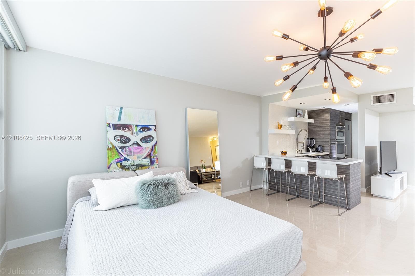 Sputnik-style chandelier, breakfast bar with horizontal wood-grain cabinetry, quartz countertops, and polished tile flooring