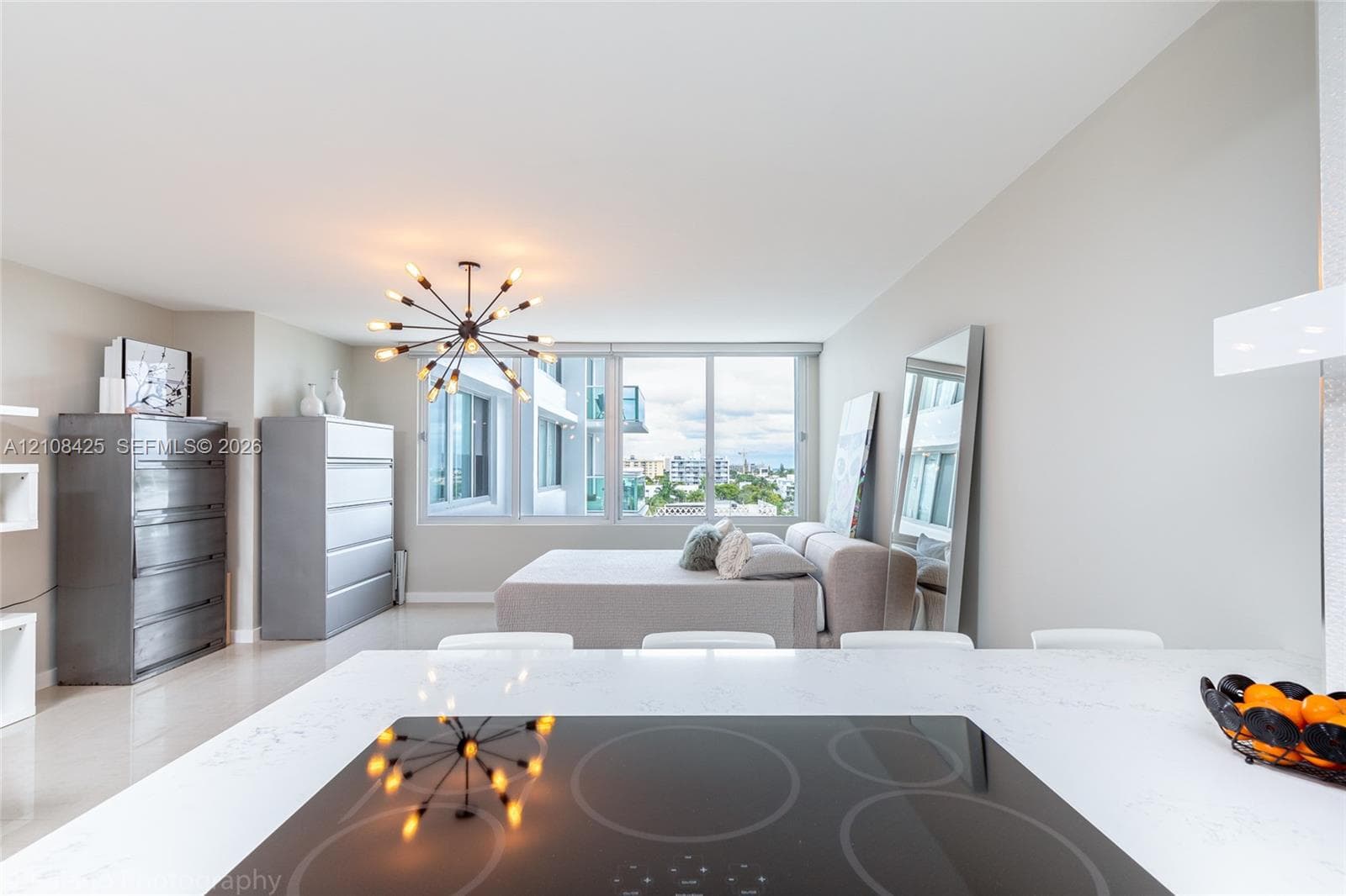 Floor-to-ceiling windows, quartz kitchen countertop, integrated induction cooktop, and multi-arm statement chandelier