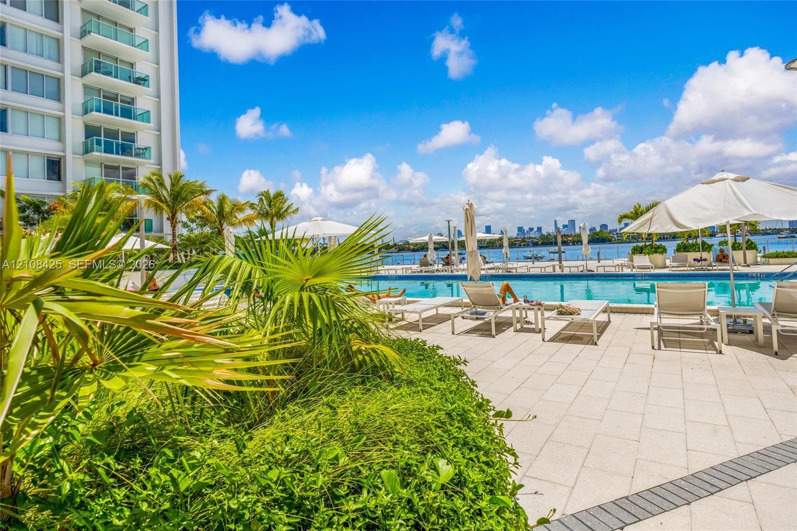 Swimming pool with stone-tiled decking, integrated landscaping, and waterfront location