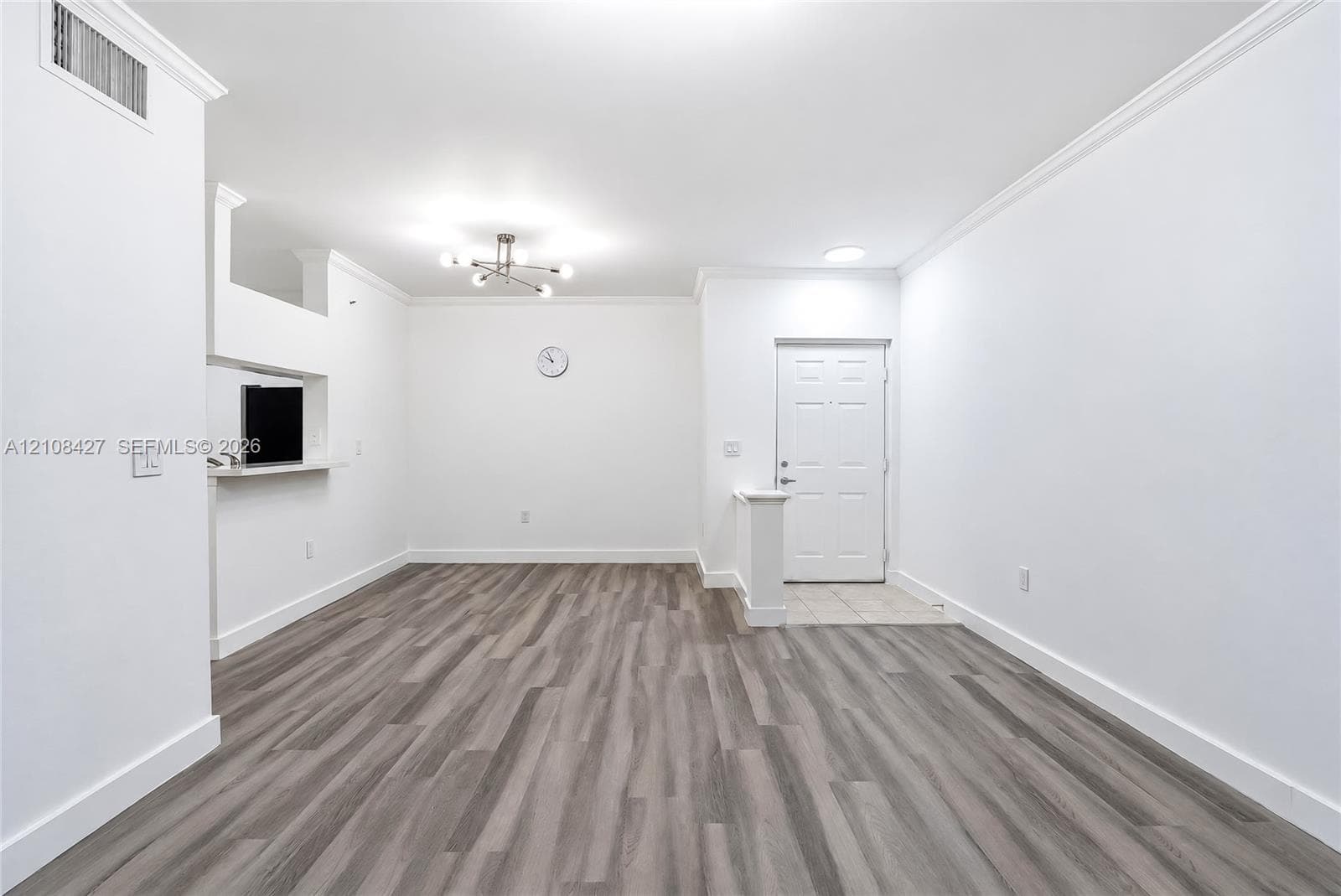 Open-concept common area featuring ceramic tile flooring, soaring tray ceilings, structural columns, built-in wooden bar cabinetry, and floor-to-ceiling glass panel doors