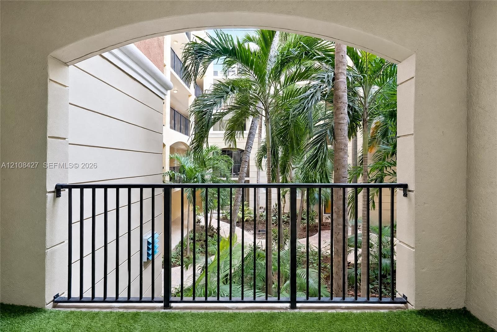 Multi-story exterior featuring a stone-facade, private waterfront promenade, arched architectural detailing, integrated balconies, and mature tropical landscaping