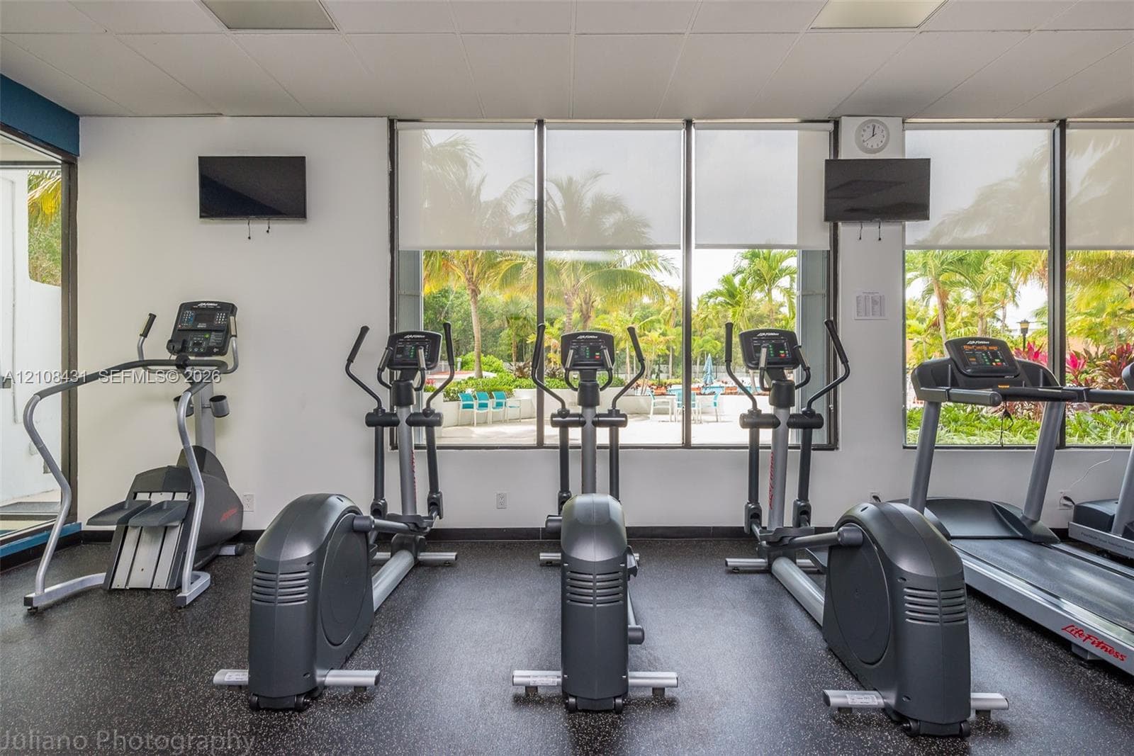 Fitness center featuring floor-to-ceiling windows, rubberized flooring, and wall-mounted televisions