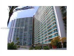 High-rise residential exterior featuring expansive glass-railed balconies and floor-to-ceiling windows