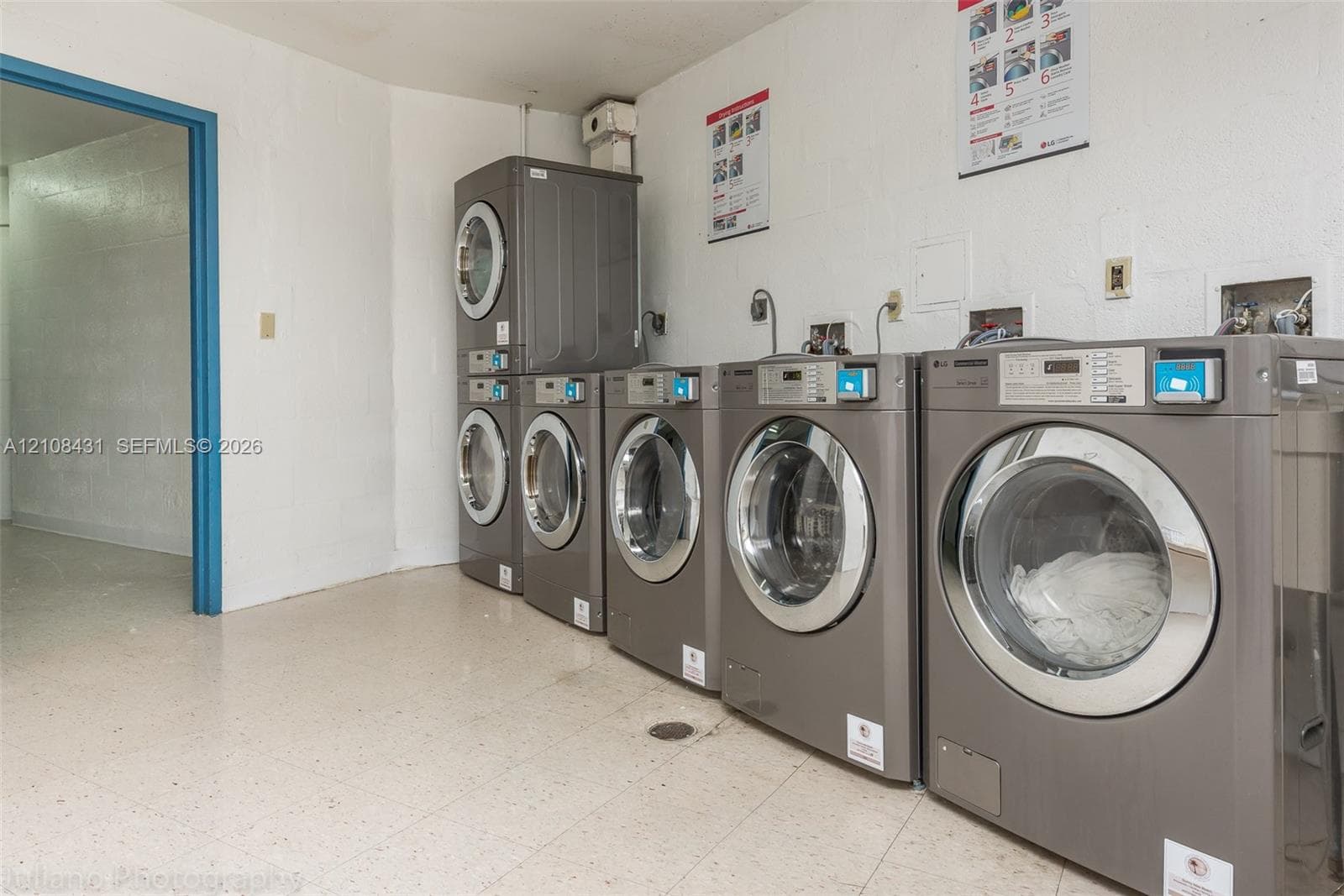 Dedicated laundry facility featuring five front-loading machines and tile flooring