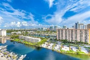 Aerial perspective of a waterway featuring boat slips, multi-story residential buildings, and surrounding urban infrastructure