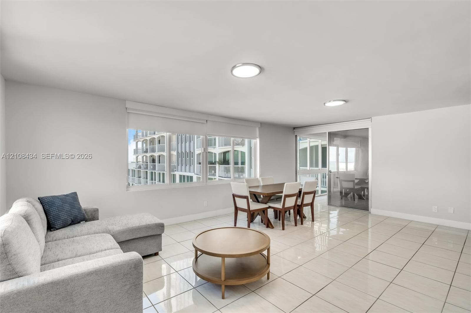 Open concept interior featuring large-format tile flooring, recessed LED lighting, expansive horizontal windows, and sliding glass balcony doors
