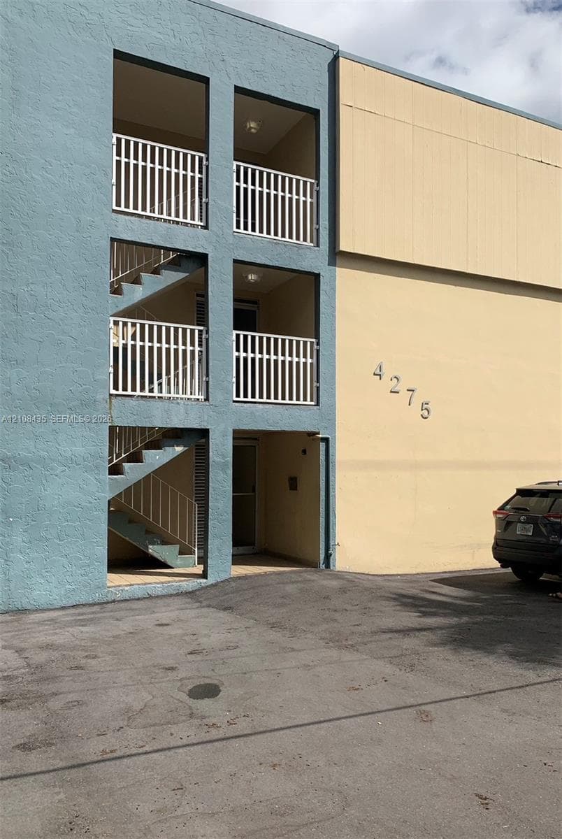 Exterior facade featuring smooth stucco finishes, tiered open-air balconies with metal railings, and integrated staircases