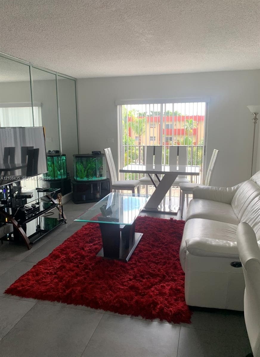 Large format tile flooring, floor-to-ceiling mirrored wall paneling, and sliding glass doors with access to an exterior balcony
