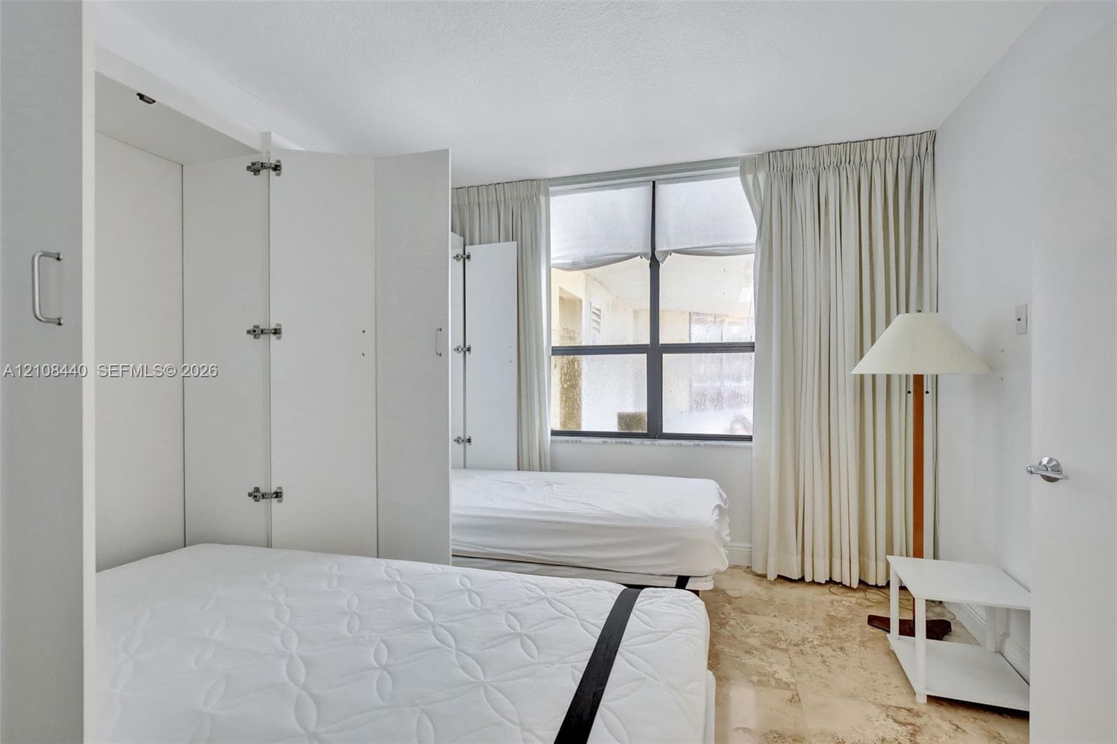 Built-in white cabinetry, natural stone flooring, and large window with dark-frame panes