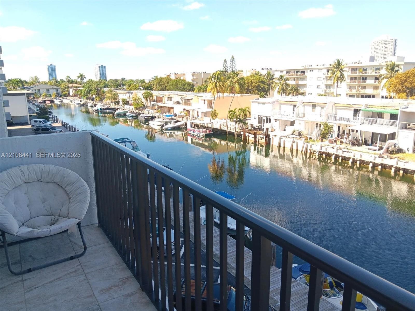 Balcony featuring tile flooring and a metal railing overlooking a canal with boat slips