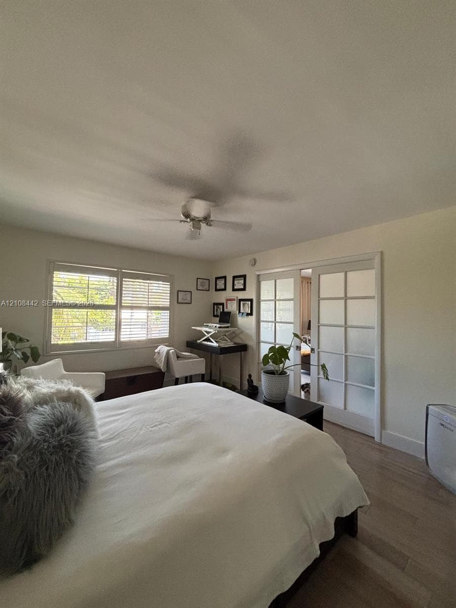 Wood-finish flooring, white-framed multi-pane sliding doors, white plantation shutters, and a ceiling fan
