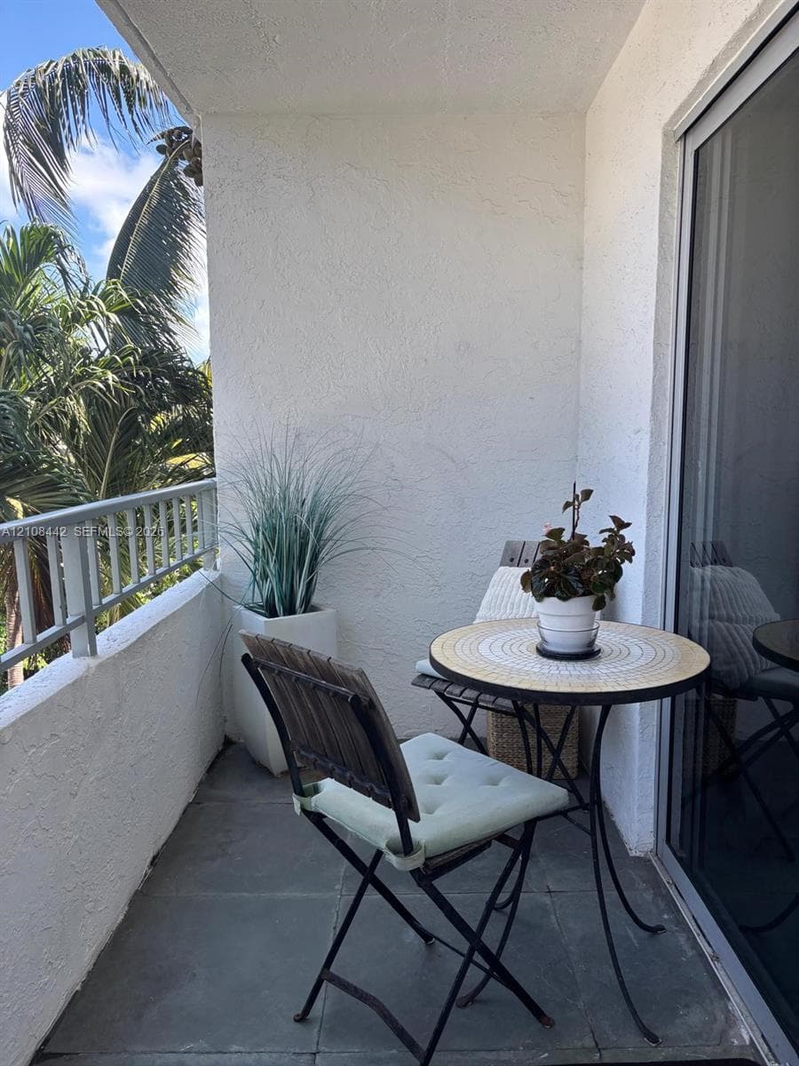 Private balcony featuring textured stucco walls, grey stone-tile flooring, and a metal railing