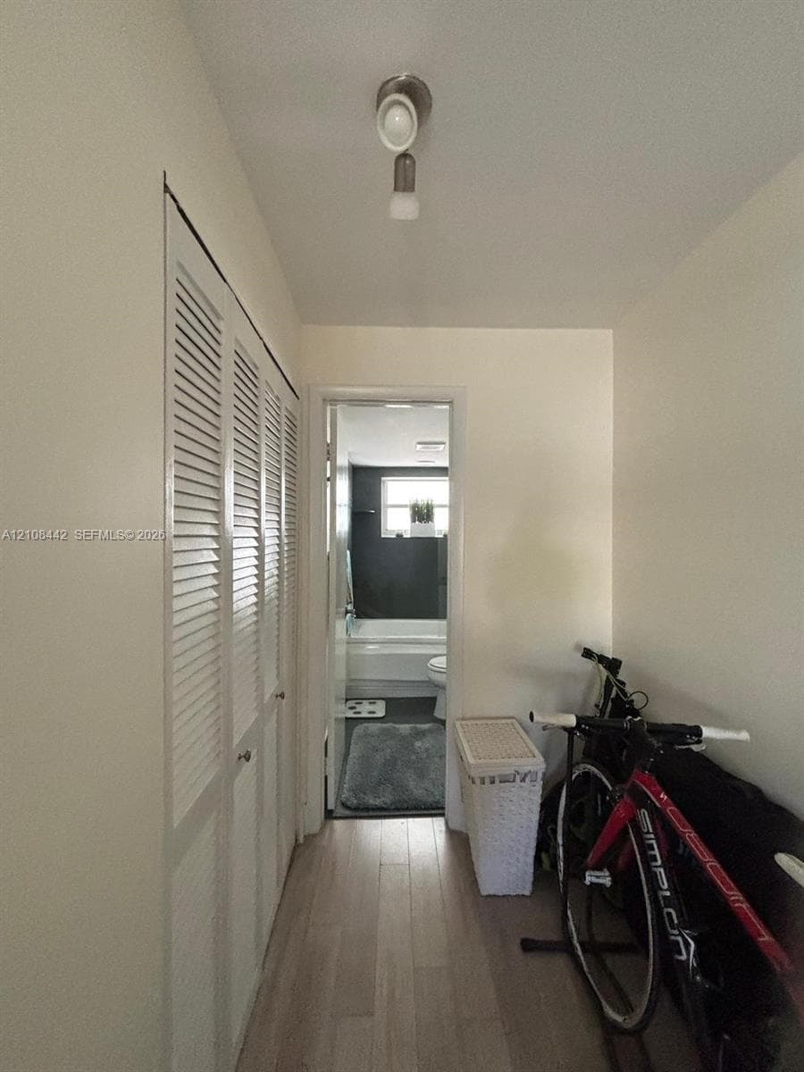 Hallway featuring louvered bi-fold closet doors, wood-finish flooring, and a ceiling-mounted light fixture