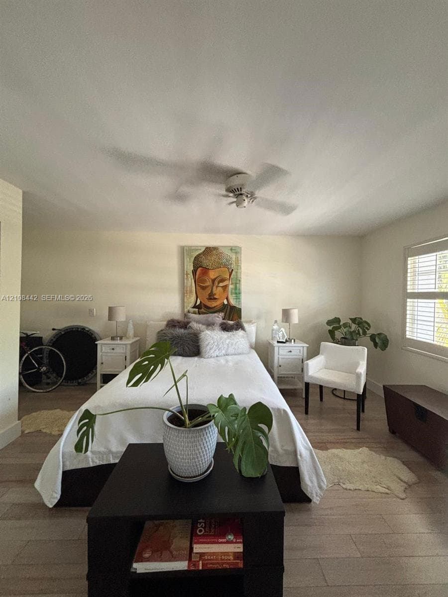 Wood-finish flooring, white plantation shutters, and a ceiling-mounted fan