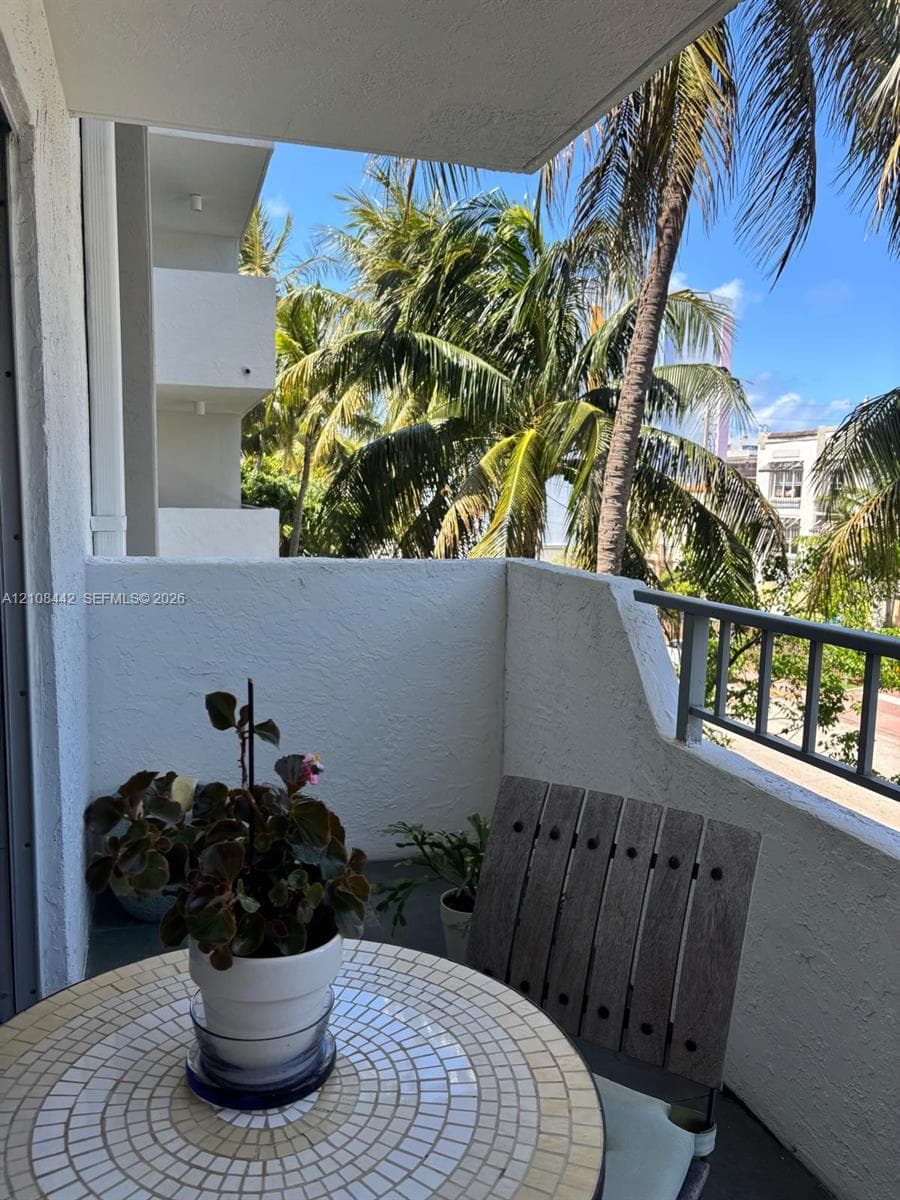 Private covered balcony featuring white textured masonry walls and a metal railing