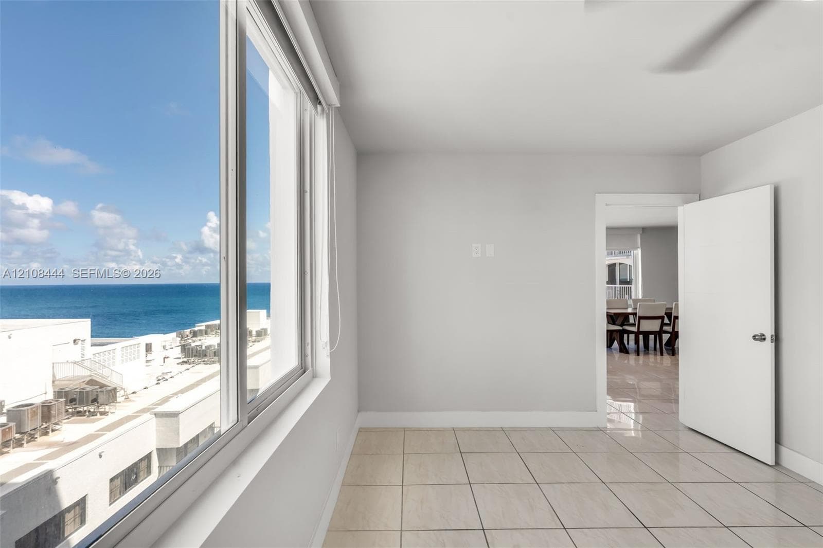 Large-format windows providing ocean scenery, neutral wall finishes, tile flooring, and a solid-core interior door