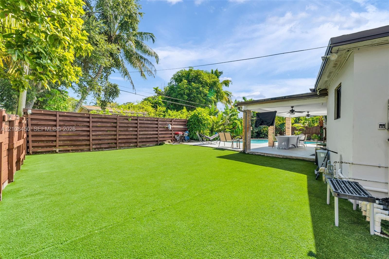 Fenced backyard featuring synthetic turf, covered patio with recessed lighting, and swimming pool
