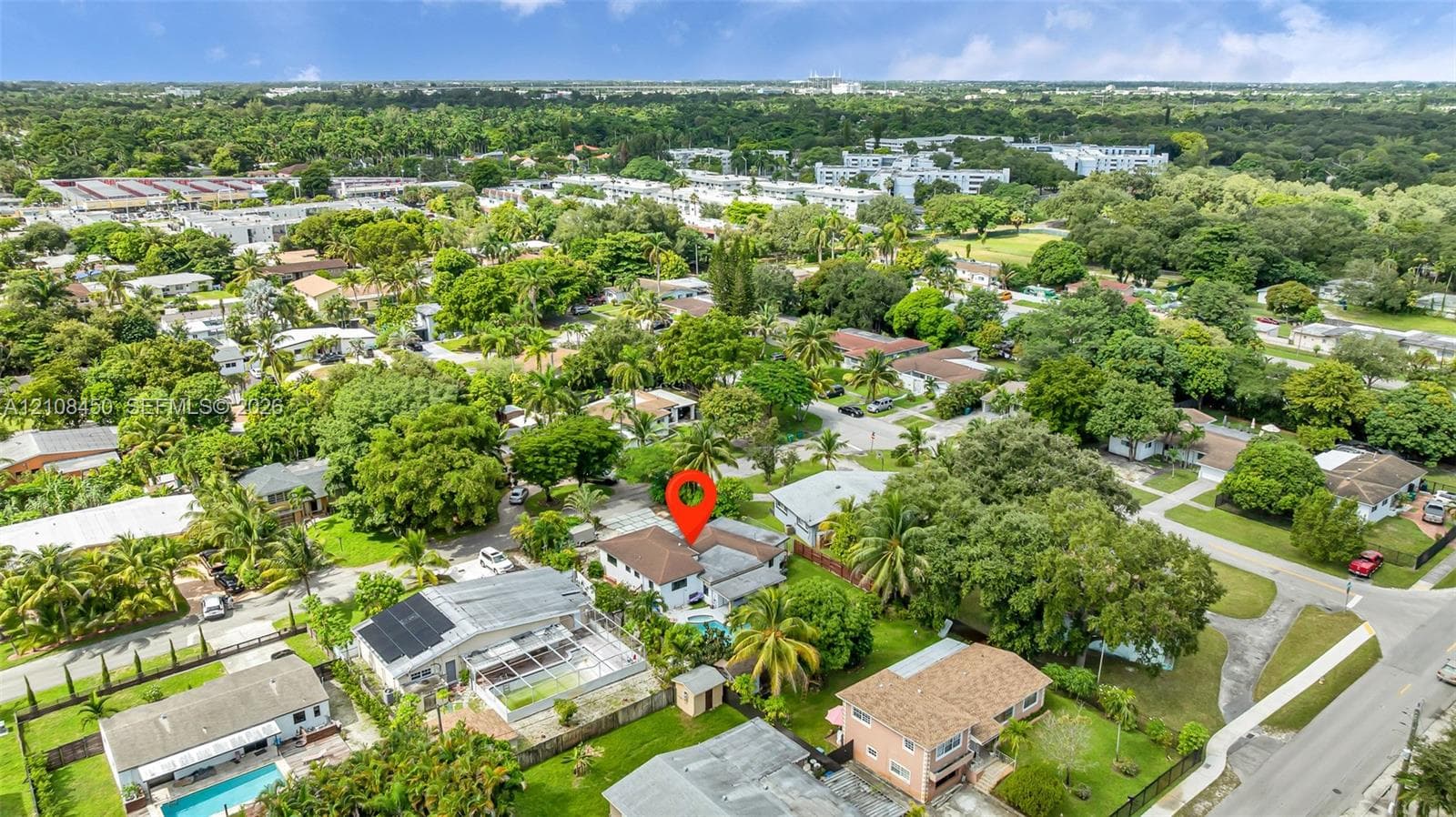 Aerial perspective of a single-family residence featuring a hipped roof and an enclosed backyard pool