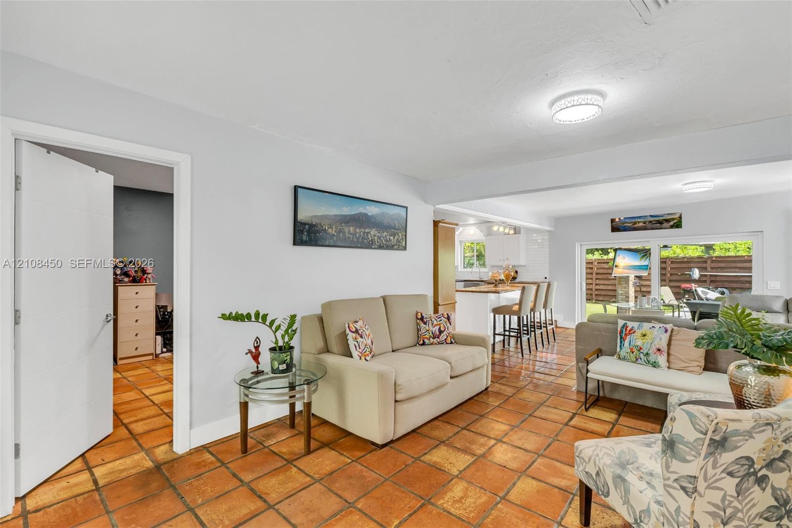 Terra cotta tile flooring, flush-mount lighting, sliding glass door, and a kitchen island with built-in cabinetry